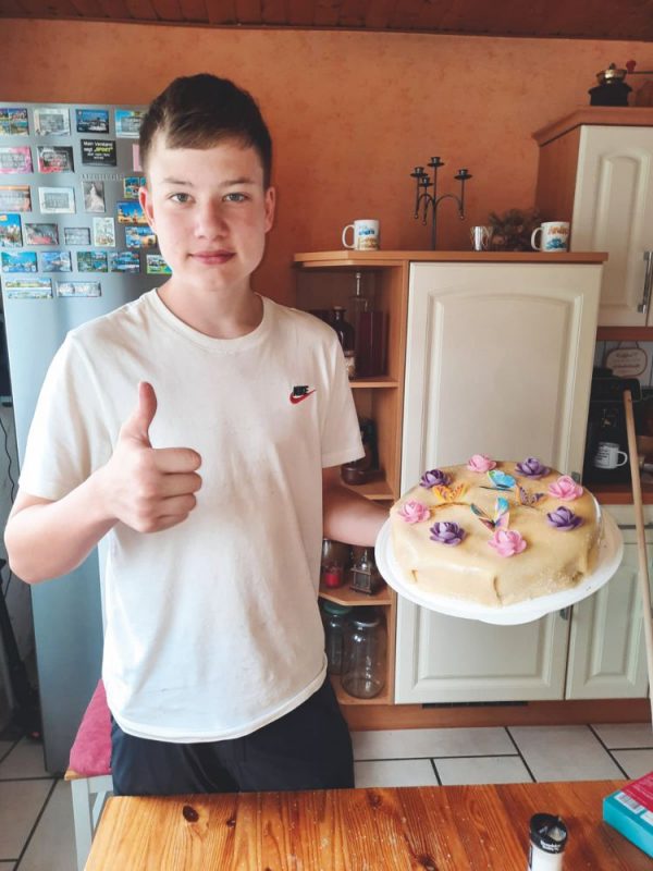 junger Bäcker mit hübsch dekoriertem Kuchen